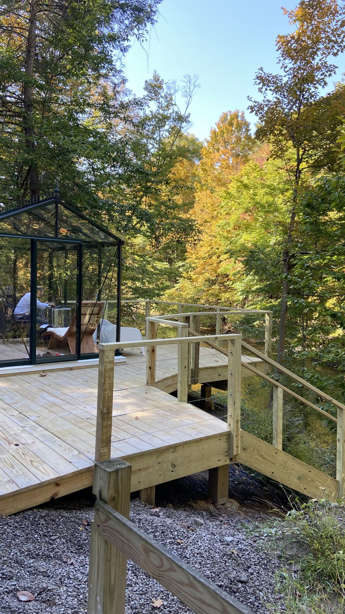 Wooden deck stairs and railings leading up to a deck with a glass greenhouse