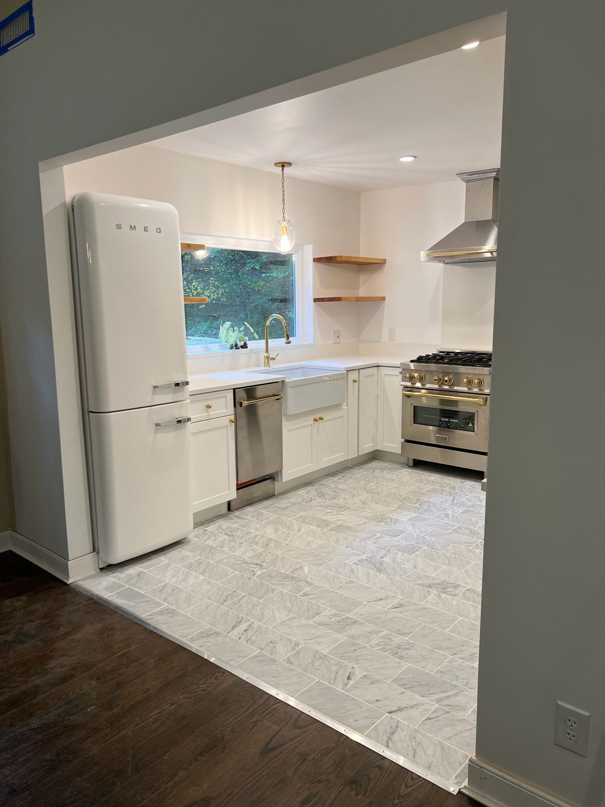 Kitchen with white cabinets, floating shelves and herringbone tile floor